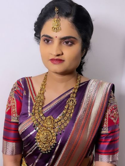 A portrait of the client, showcasing her complete traditional look. The makeup is balanced to harmonize with her purple Kanjeevaram saree and antique gold jewelry.
