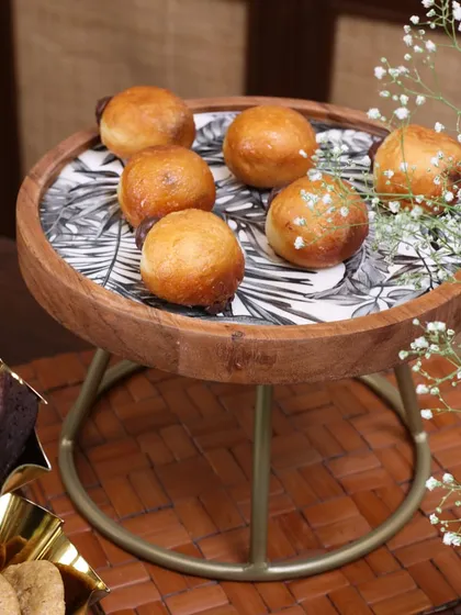 The Moon Ray multipurpose serving stand, featuring a wooden top with a monochrome leaf print and a sleek metal base. It’s a perfect blend of natural and modern aesthetics.