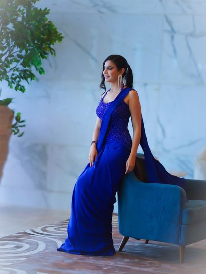 A full-length pose against a blue chair, demonstrating how to style a monochromatic look with elegance.