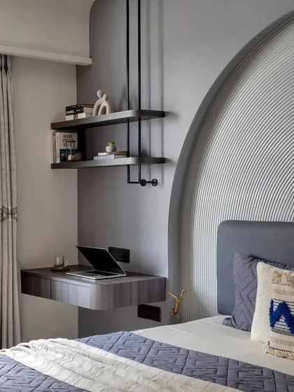 A floating desk and suspended shelves create a functional and stylish workspace within the bedroom, maintaining a light and uncluttered feel.