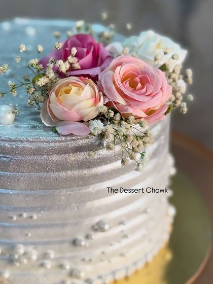 A close-up of the floral arrangement on a silver 25th anniversary cake. I use a mix of artificial flowers and baby's breath to create a beautiful, lasting design.