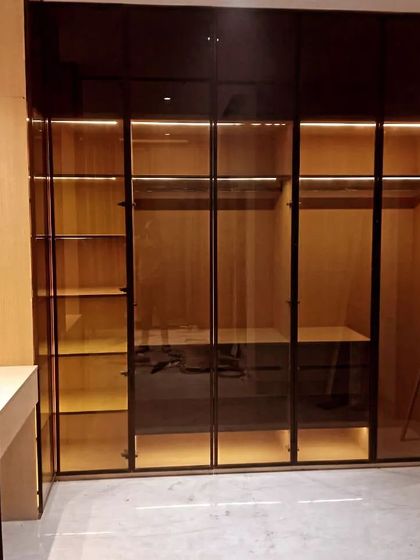 This image showcases a fully fitted glass wardrobe with internal lighting on, highlighting the different storage zones we created for hanging, shelving, and drawers.
