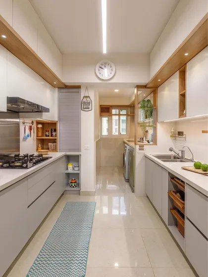 This long galley kitchen is designed for efficiency, with sleek grey cabinets, integrated appliances, and open wooden shelving for easy access to everyday items.