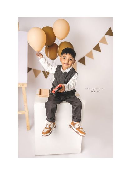 A three-year-old boy holding balloons during his teddy bear themed birthday shoot.