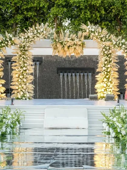 For a 25th anniversary, we created this ethereal sundowner celebration over water. The all-white floral arch against the cascading waterfall backdrop speaks of timeless elegance and enduring love, making for a truly exquisite milestone.