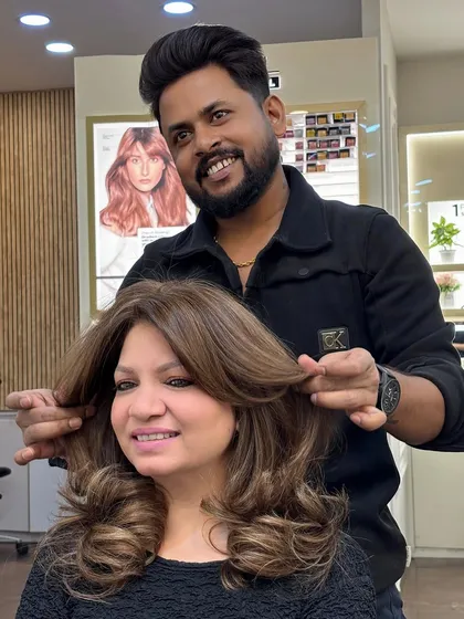 A happy client showing off her new caramel blonde hair. The color is rich and warm, and the style is full of volume.