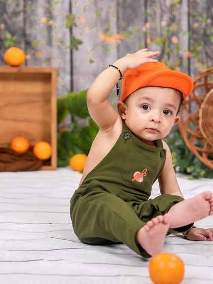 A playful moment during a sitter session. The little one is adjusting his cap, showing off his budding personality for the camera.