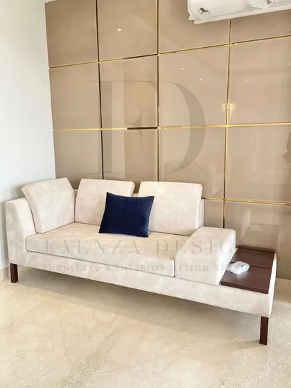 A custom daybed designed for a living room corner. This versatile piece features a built-in wooden side table, making it a perfect spot for lounging, reading, or hosting an extra guest.