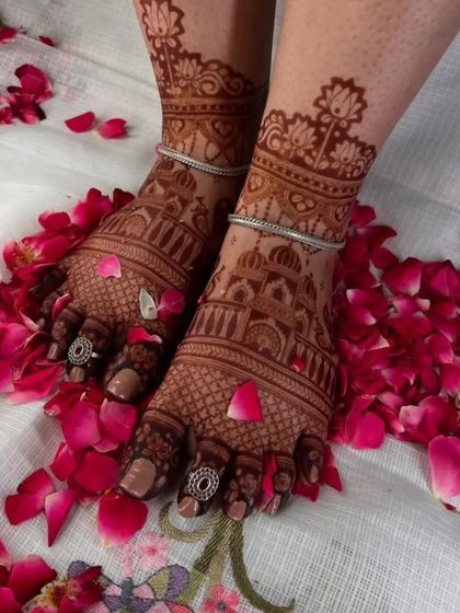 This stunning foot mehendi features palace architecture and is accessorized with traditional silver toe rings and anklets, completing the bridal look.