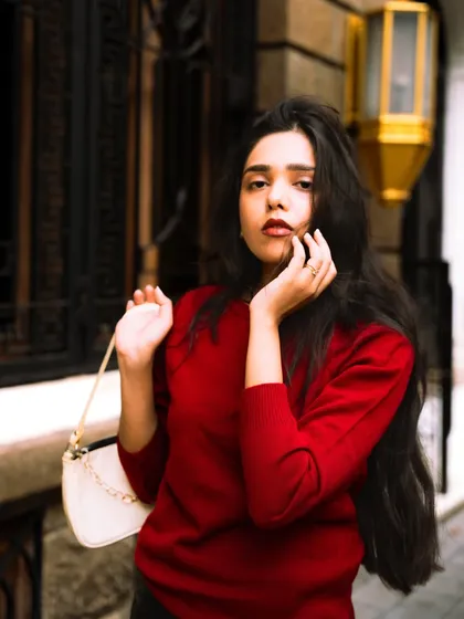 A close-up shot focusing on the model's expression and the details of her outfit. The soft background keeps the attention on her.