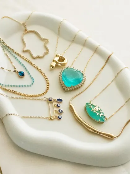 Good vibes only. This flat lay shows off some of my favorite evil eye and hamsa necklaces, perfect for layering or wearing alone.