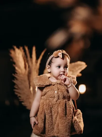 A curious little squirrel. This imaginative portrait captures a toddler in a cute costume, looking thoughtfully to the side against a dark, dramatic background.