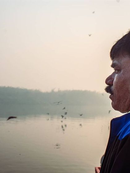 A portrait of a man watching the birds fly over the river. His contemplative profile against the hazy background tells a story of a quiet moment of reflection.