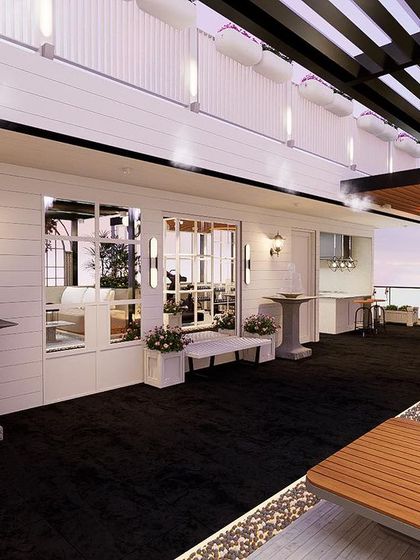 This image shows the length of the terrace, highlighting the white shiplap walls, classic lanterns, and the contrast of the dark flooring, all contributing to the French-inspired aesthetic.
