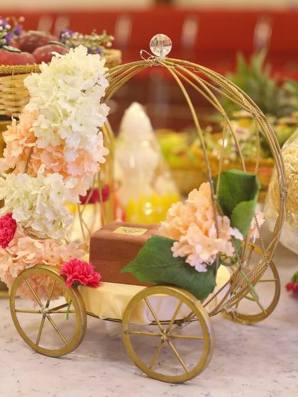 A unique and elegant prop for an engagement or wedding. This golden carriage, decorated with pastel flowers, can be used to hold rings or other small, significant items.