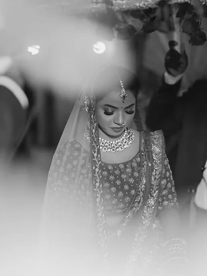 An artistic shot of the bride's entrance. The use of foreground blur creates a dreamy, cinematic effect, focusing all attention on the bride.