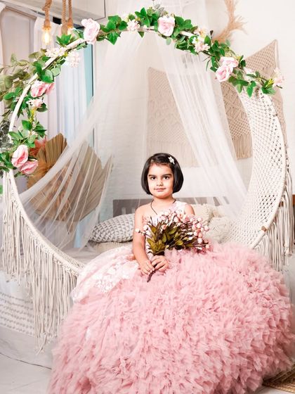 Here’s another princess enjoying her shoot on our boho-themed hanging chair set. She is wearing a gorgeous pink ruffled gown and holding a bouquet, looking like she stepped right out of a storybook.