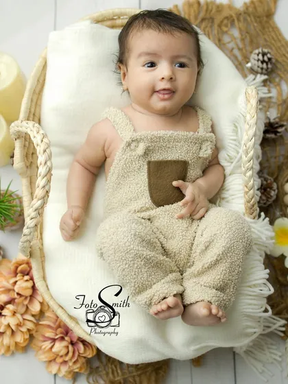 A sweet, subtle smile from this little boy in his cozy overalls. The boho setup is perfect for capturing these relaxed, awake moments.
