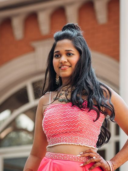 A beautiful shot of the bride in a chic half-up, half-down top knot hairstyle. This modern look is perfect for pre-wedding events, keeping hair off the face while still showing off its length and texture.