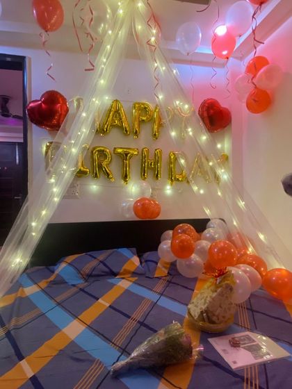 Another angle of the fairy light cabana setup. You can see how the warm lights and balloons work together to create a dreamy and romantic ambiance for a birthday surprise. A bouquet of flowers on the bed adds a finishing touch.