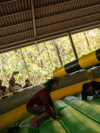 A participant gets knocked off his feet by the rotating arm in the Meltdown game, while his teammates watch and laugh.