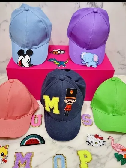 A display of our colorful caps and a selection of the many patches available for customization. Guests can choose from initials, characters like Mickey Mouse, and other fun icons to create their perfect cap.