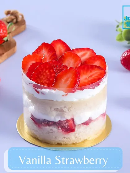 A beautiful shot of our Vanilla Strawberry mini dessert. The clear acetate collar showcases the neat layers of vanilla sponge, strawberry filling, and fresh cream, topped with sliced strawberries.