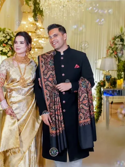 A beautiful couple makes their entrance at a reception filled with ethereal smoke and bubbles. The bride's gold saree and the groom's classic bandhgala perfectly match the elegant decor.