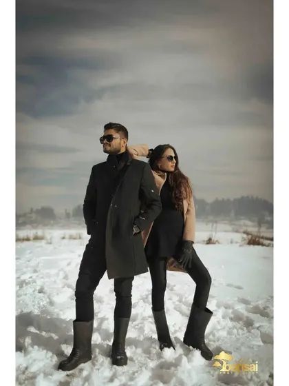 A stylish, editorial-style pose in the snow. The couple's chic winter outfits and confident stance make for a powerful and fashionable pre-wedding photo.
