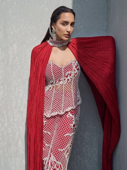 A fully pearl-embellished corset paired with tailored pants and a sweeping crushed cape that doubles as a dramatic choker. This is elegance with an edge.