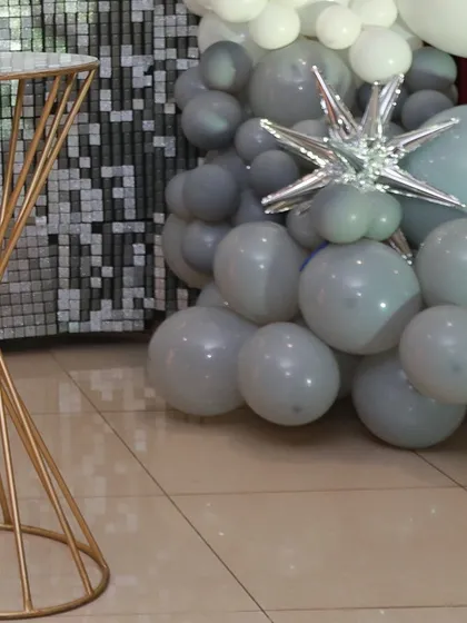 A detail shot showing the combination of the spiral pedestal, balloon garland, and sequin wall for a chic anniversary party.