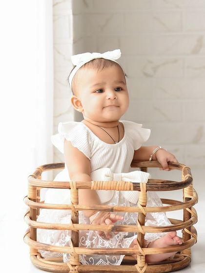A simple and serene portrait. The clean white background and natural wicker basket create a timeless and classic baby photo.