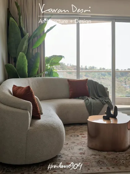 A view of the living room in Row House 904, showcasing the curved boucle sofa and organic-shaped coffee table. The design emphasizes natural forms and textures to create a peaceful retreat.