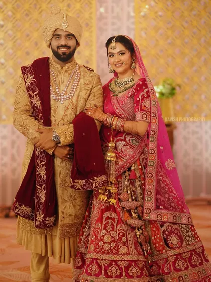 A classic wedding portrait of the bride and groom in their traditional attire, smiling for the camera.