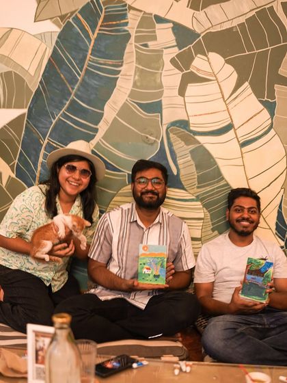 Three participants pose with a kitten and their artwork against a beautiful mural.