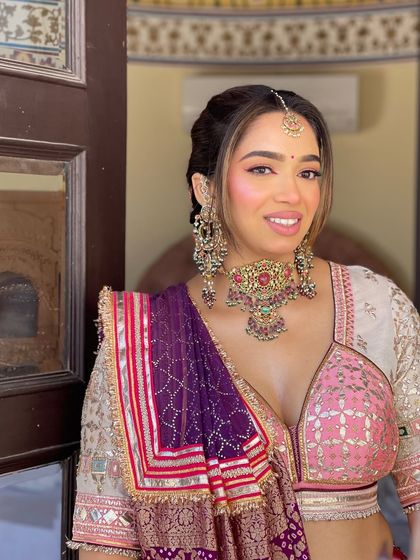 A close up of the bride's happy face. The front of her hair is styled with a soft puff and face framing tendrils to complement the braid at the back.