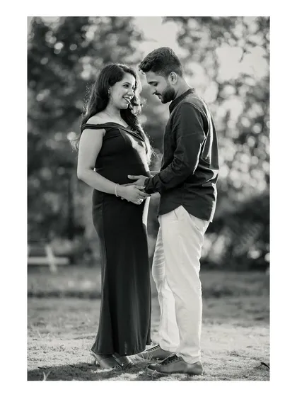 A timeless black and white photo of an expecting couple sharing a quiet, happy moment together outdoors. This classic style emphasizes the emotional connection and anticipation.