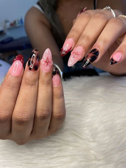 I'm obsessed with this moody and complex set. It combines tortoise shell art, deep red French tips, and delicate 3D floral details for a truly unique and screenshot-worthy manicure.