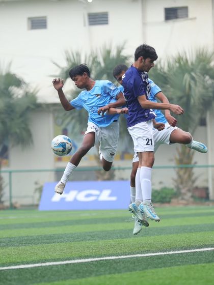 Fierce, focused, and flying high. Two players jump for a header, a common sight in our action-packed games.