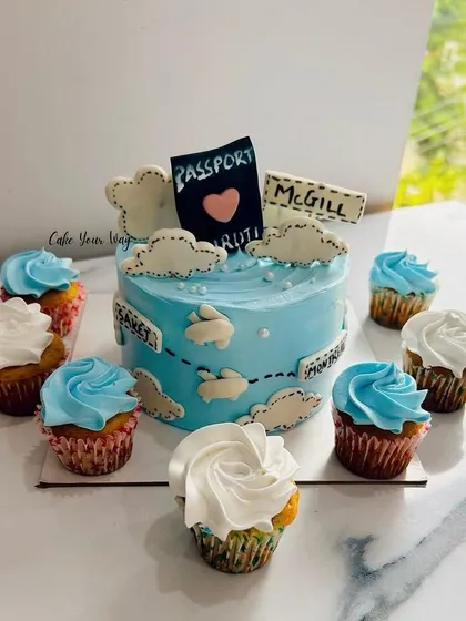 A cute farewell cake with a travel theme, complete with a passport and cupcakes as clouds.