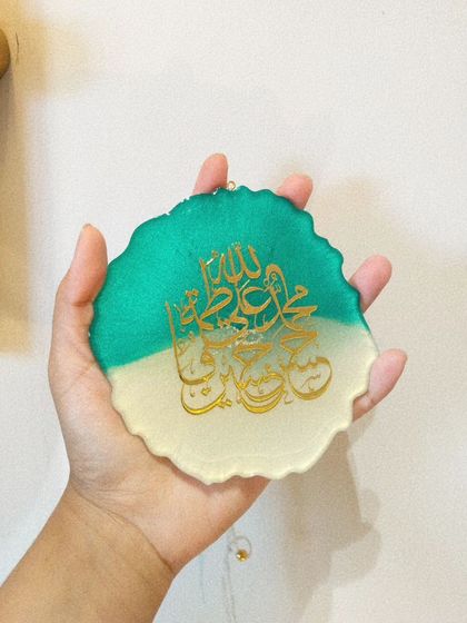 Holding the two-tone Islamic calligraphy car hanging to show its size and the quality of the finish.