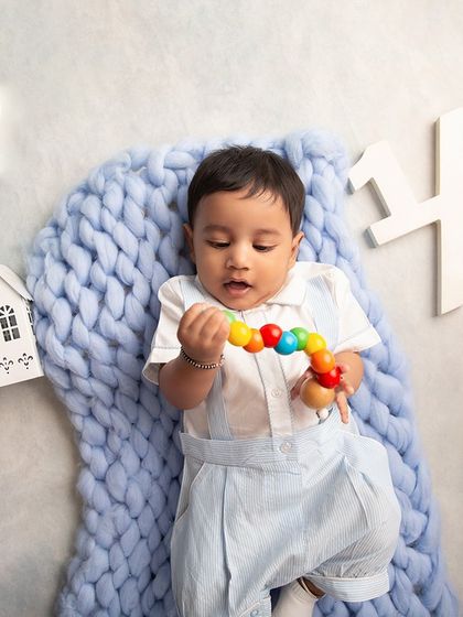 Celebrating a half-birthday milestone. This flat-lay style photo shows the baby on a soft blue blanket, surrounded by props that mark his six-month celebration.