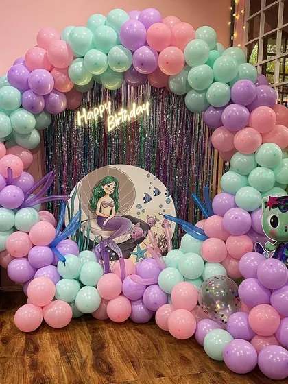 A beautiful pastel mermaid theme, featuring a soft-colored balloon arch and a cute mermaid character backdrop for a dreamy under-the-sea party.