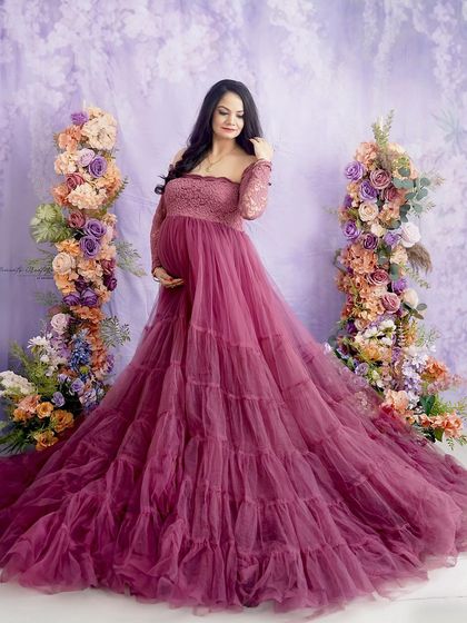 A vision in lavender and mauve. Standing between two floral pillars, the mom-to-be looks serene and beautiful in this pastel-toned portrait.