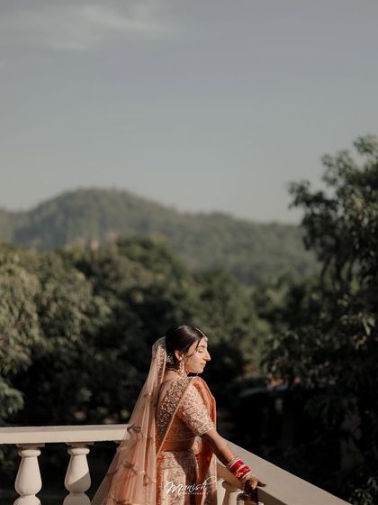 A serene bridal portrait on a balcony overlooking a lush, green landscape, capturing a moment of peace before the ceremony.