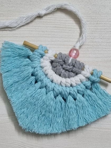 A colorful mini macrame fan, perfect as a car charm or a small hanging ornament.
