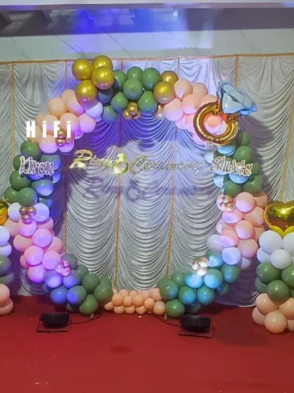 For your ring ceremony, I can create a beautiful and symbolic backdrop. This setup uses a circular balloon arch in olive green and peach, accented with a large diamond ring foil balloon and custom lettering for the couple's names, making the moment picture perfect.