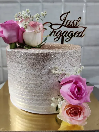 An elegant engagement cake to celebrate a special commitment. This cake is finished with a sparkling shimmer and adorned with fresh pink roses and baby's breath.