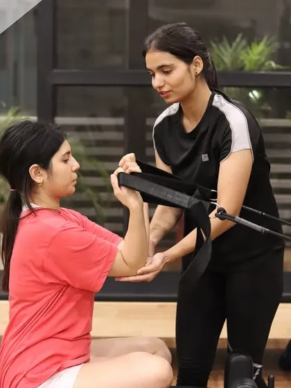 A trainer helps a client with hand placement and posture. These small adjustments make a big difference in activating the correct muscle groups and achieving the full benefit of the exercise.