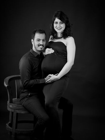 A classic black and white studio portrait. The couple poses formally, creating a sophisticated and timeless image.
